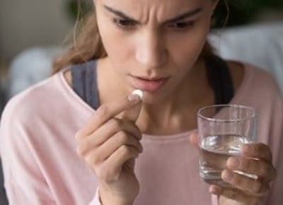Eine Frau, die eine Pille nimmt und besorgt aussieht