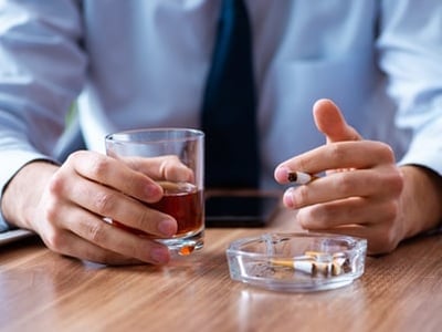 Een man drinkt alcohol en rookt