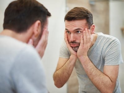 Een man kijkt ontstresst in de spiegel