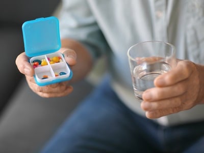 Oudere man met container met medicijnen
