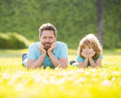 Een vrolijke vader en zijn dochter ontspannen op het gras in het park en genieten van een zonnig moment.